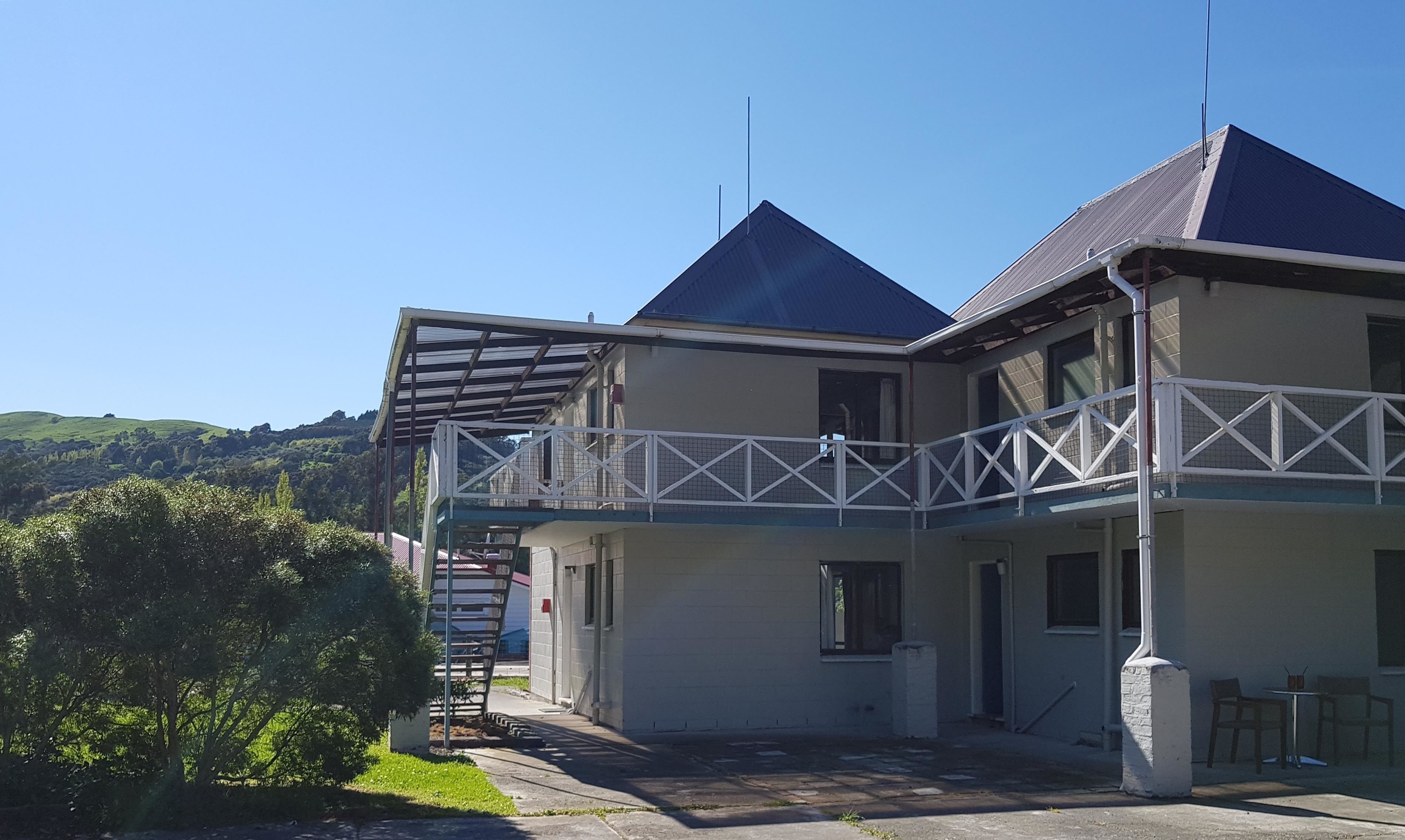 Un edificio de dos pisos con un balcón y un espacio al aire libre cubierto.