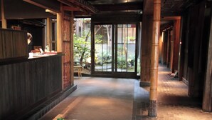 A traditional interior with a stone basin filled with green fruits, wooden pillars, and a view of the outside garden. - Yuzuya Ryokan - Adult Only (Kyoto)