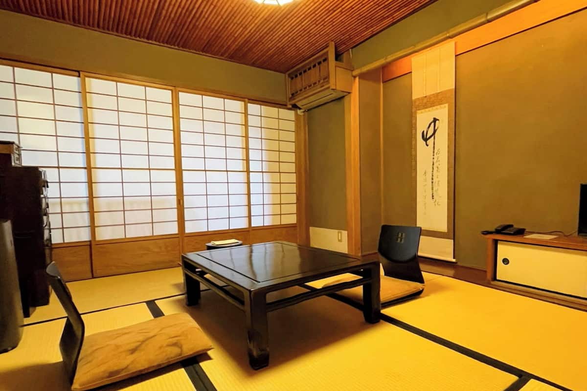 Une pièce de style japonais traditionnel, avec un sol recouvert de tatamis, une table basse, une chaise et une porte coulissante dotée de panneaux shoji.