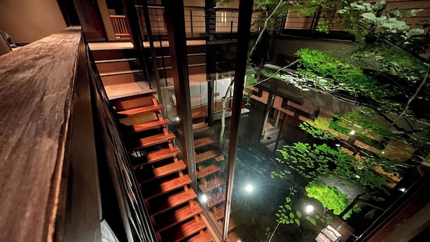 A multi-level wooden staircase leading to a lower level with a garden area visible through glass railings. - Yuzuya Ryokan - Adult Only (Kyoto)
