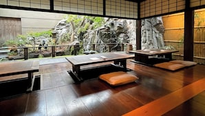A traditional Japanese-style room with tatami flooring, low tables, and cushions. - Yuzuya Ryokan - Adult Only (Kyoto)
