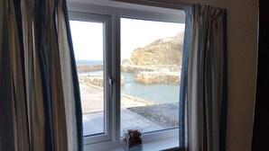 A room with a large window overlooking a rocky coastline and a harbor. - BEAUTIFUL HARBOURSIDE COTTAGE, 2 MIN WALK TO BEACH, special offer from £595/week (Portreath)
