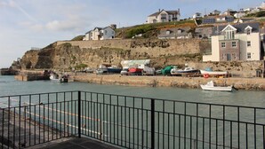 A coastal town with houses on a cliff, a marina with boats, and a stone wall. - BEAUTIFUL HARBOURSIDE COTTAGE, 2 MIN WALK TO BEACH, special offer from £595/week (Portreath)