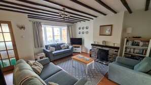 A living room with a sofa, a coffee table, a fireplace, and a bookshelf. - BEAUTIFUL HARBOURSIDE COTTAGE, 2 MIN WALK TO BEACH, special offer from £595/week (Portreath)