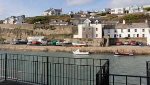 A coastal town with houses on a hillside, a marina with boats, and a stone wall. - BEAUTIFUL HARBOURSIDE COTTAGE, 2 MIN WALK TO BEACH, special offer from £595/week (Portreath)