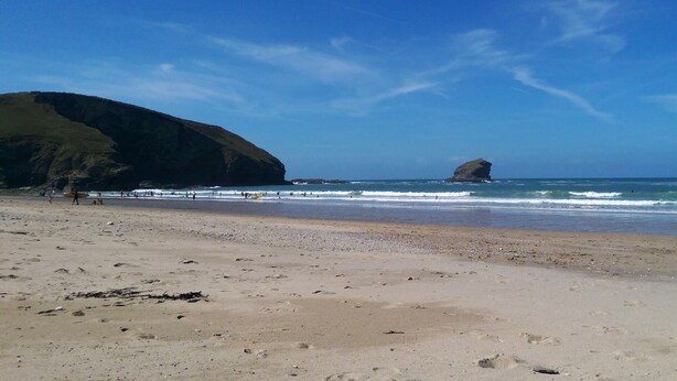 A beach with a large rock formation in the distance, sandy shore, and clear blue sky. - BEAUTIFUL HARBOURSIDE COTTAGE, 2 MIN WALK TO BEACH, special offer from £595/week (Portreath)
