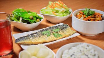 Un tavolo con diversi piatti, tra cui pesce, insalata e riso.