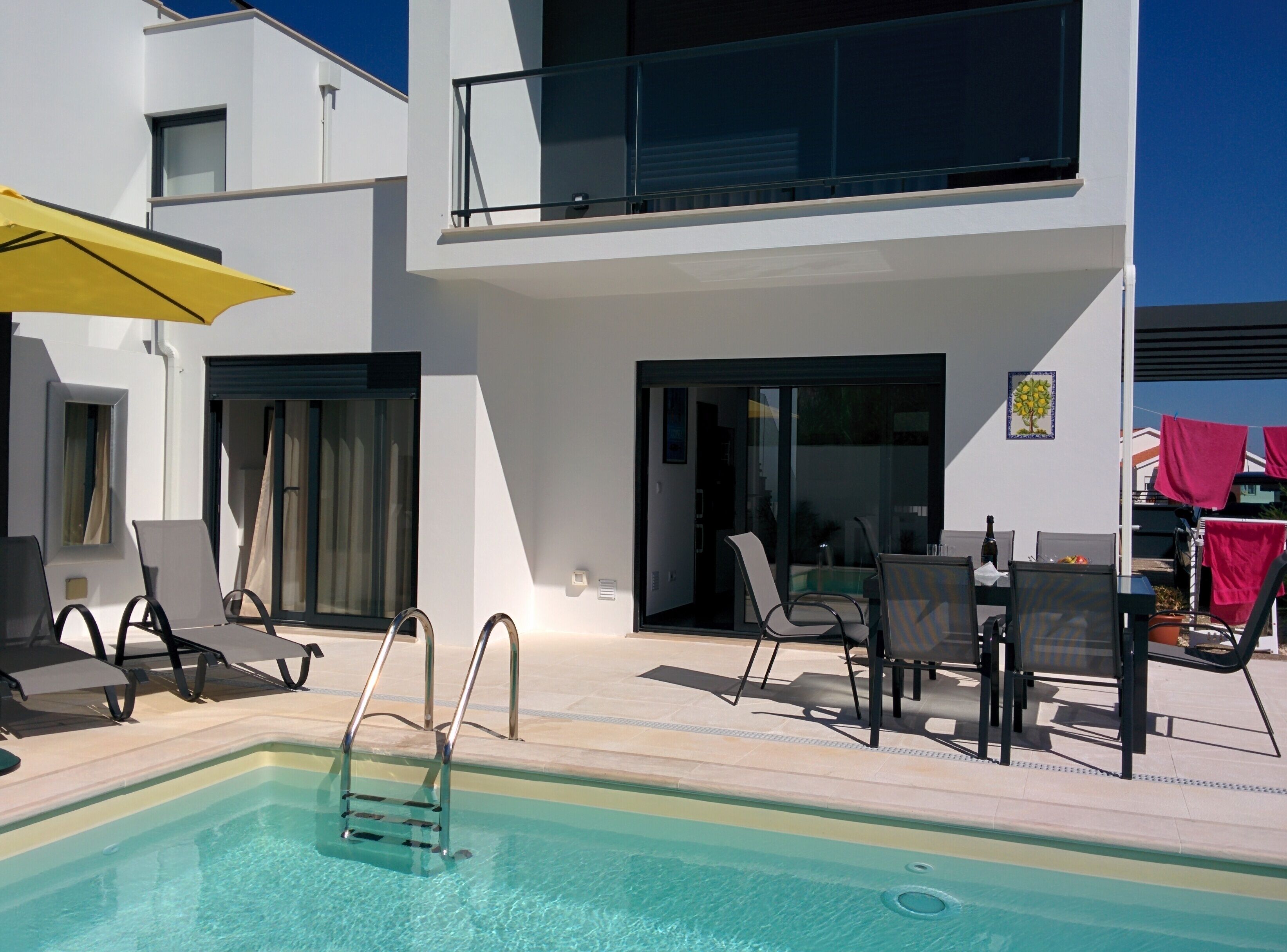 Ein moderner Poolbereich im Freien mit klarem Pool, Liegestühlen und einem Essbereich mit Stühlen.