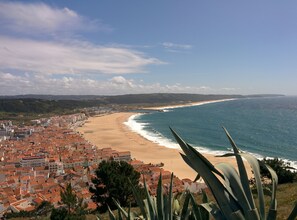 En kystby med tage af terracotta, en sandstrand og udsigt over havet.