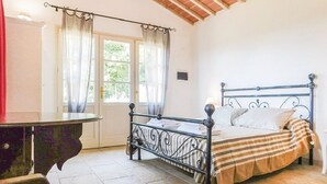 A bedroom with a metal bed frame, a striped bedspread, and a window with curtains. - Tuscany: House "Old Abbey" among the olive trees with pool (Monteverdi Marittimo - PI -)