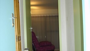 A room with a red sofa, a wooden door, and a tiled floor.