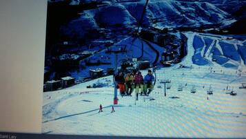 A ski resort with a chairlift, skiers, and a snowy landscape.