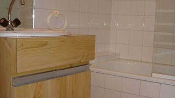 Une salle de bain avec un meuble-lavabo en bois, un évier et une baignoire.