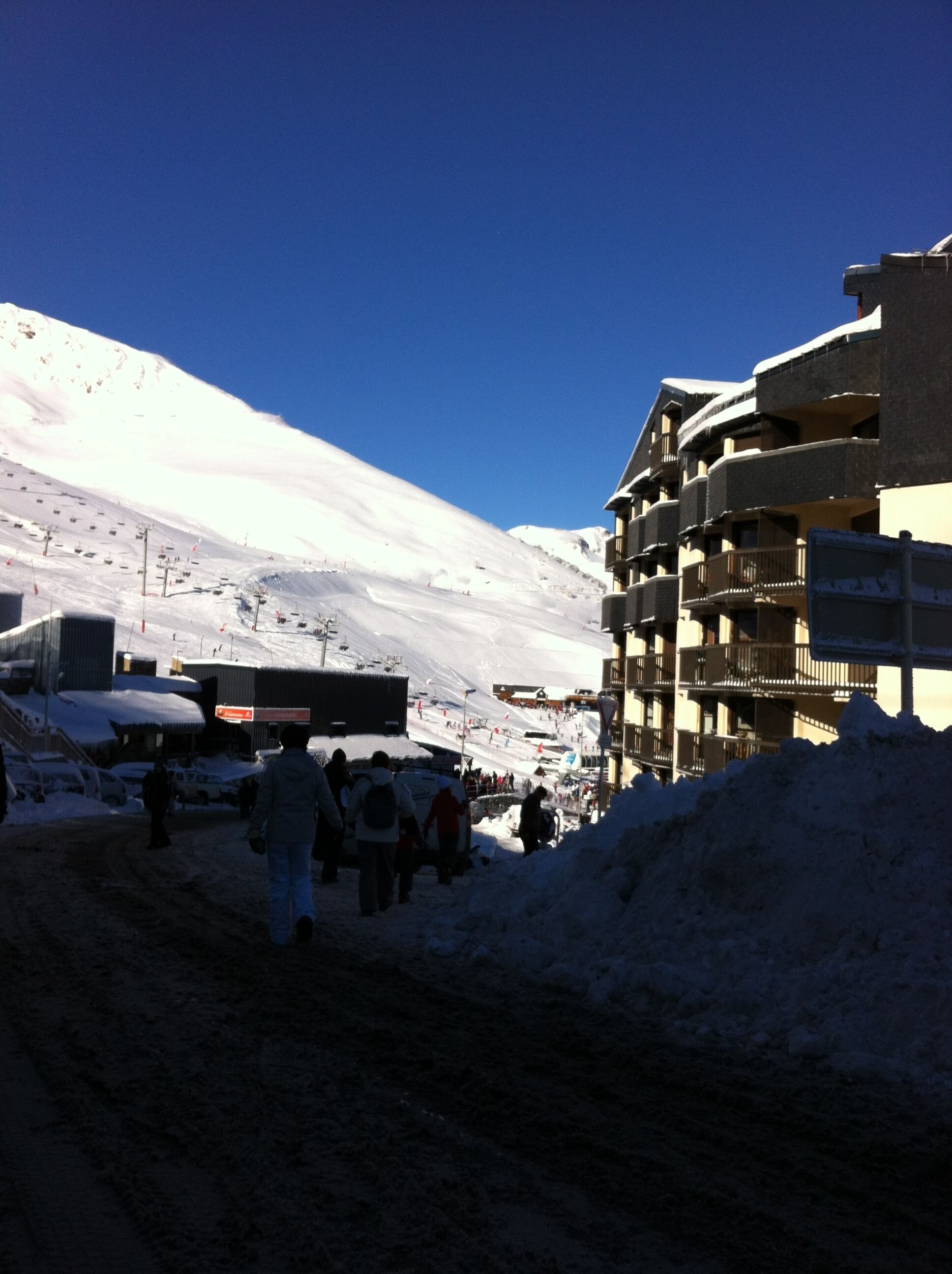 A snow-covered mountain with a ski lift and a building with balconies.
