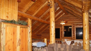 Ein Blockhaus-Interieur mit Holzbalkendecke, einer Couch und einem Bett.
