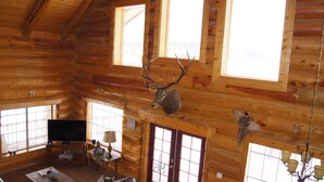 Ein Holzblockhaus-Interieur mit Fernseher, Kamin und einem an der Wand befestigten Hirschkopf.