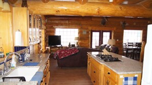 Ein Holzblockhaus-Innenraum mit Küche, Essbereich und Wohnzimmer mit Kamin.