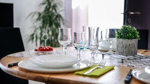 A dining table set with plates, cutlery, and glasses, with a potted plant and a bowl of fruit on the table. - Grand T3 60 m², pool, 2 parking, 4 bikes, Beach, Shops, Marina Port (Saint-Cyprien)