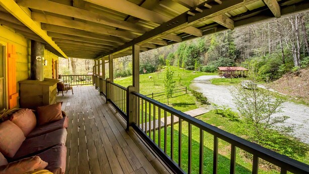 A covered porch with a view of a river and forest. - Private Riverfront Cabin: 9 Acres,  Trails to Waterfalls (Sapphire)
