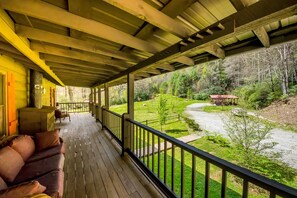 A covered porch with a view of a river and forest. - Private Riverfront Cabin: 9 Acres,  Trails to Waterfalls (Sapphire)
