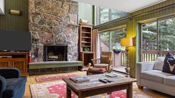 A cozy living room with a stone fireplace, a television, and a comfortable seating area with a sofa and armchairs.