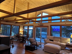 A spacious room with a high ceiling, large windows, and a cozy seating area. - Oceanfront Maine Acadia Cottage (Hancock)