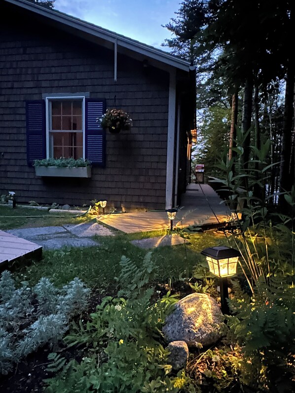 A house with a brick exterior, a window with shutters, and a pathway leading to the entrance.