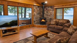 Una sala de estar acogedora con chimenea de piedra, un sofá cómodo, televisor y bañera de hidromasaje.