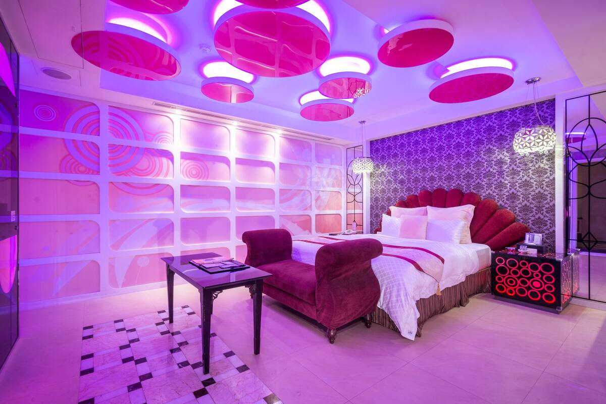 Een moderne slaapkamer met een groot bed, een rode bank en een klein tafeltje.
