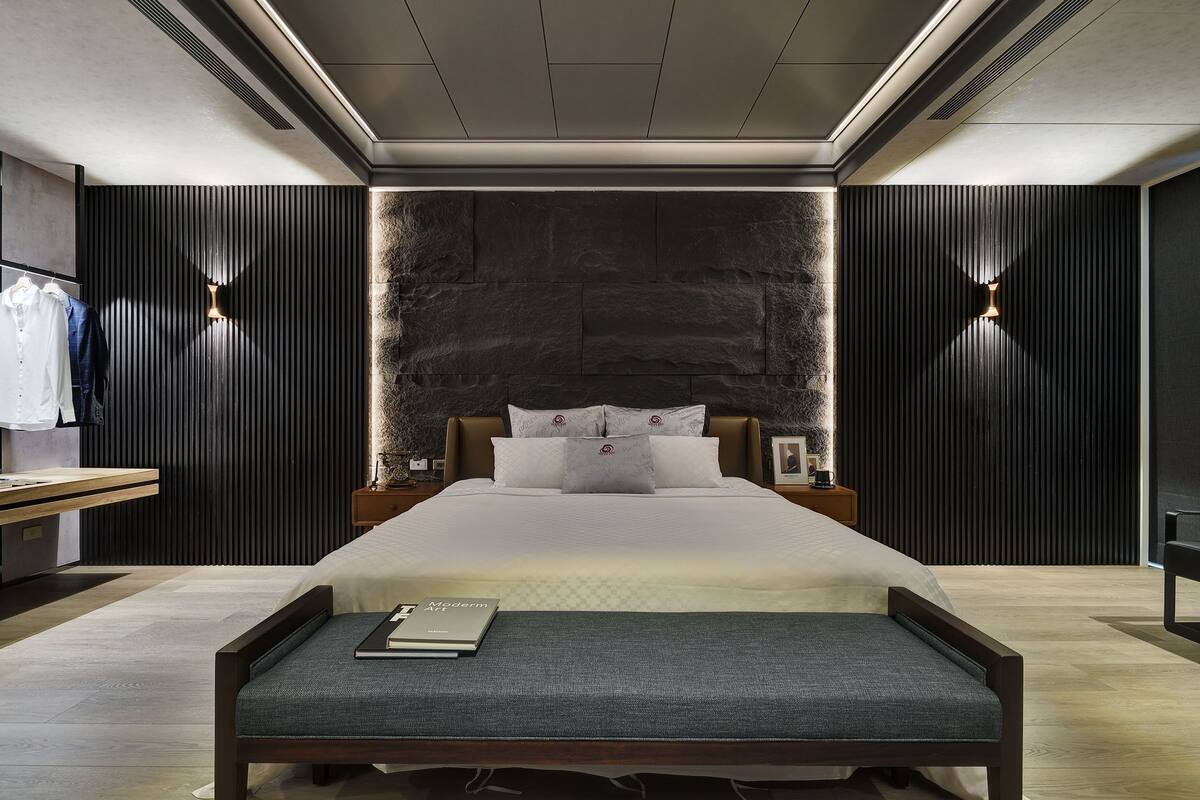 Een moderne slaapkamer met een groot bed, nachtkastjes en een bankje.