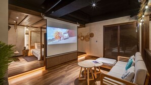 Un saló modern amb terra de fusta, un sofà, una taula petita i una pantalla de projector que mostra una escena de desert.