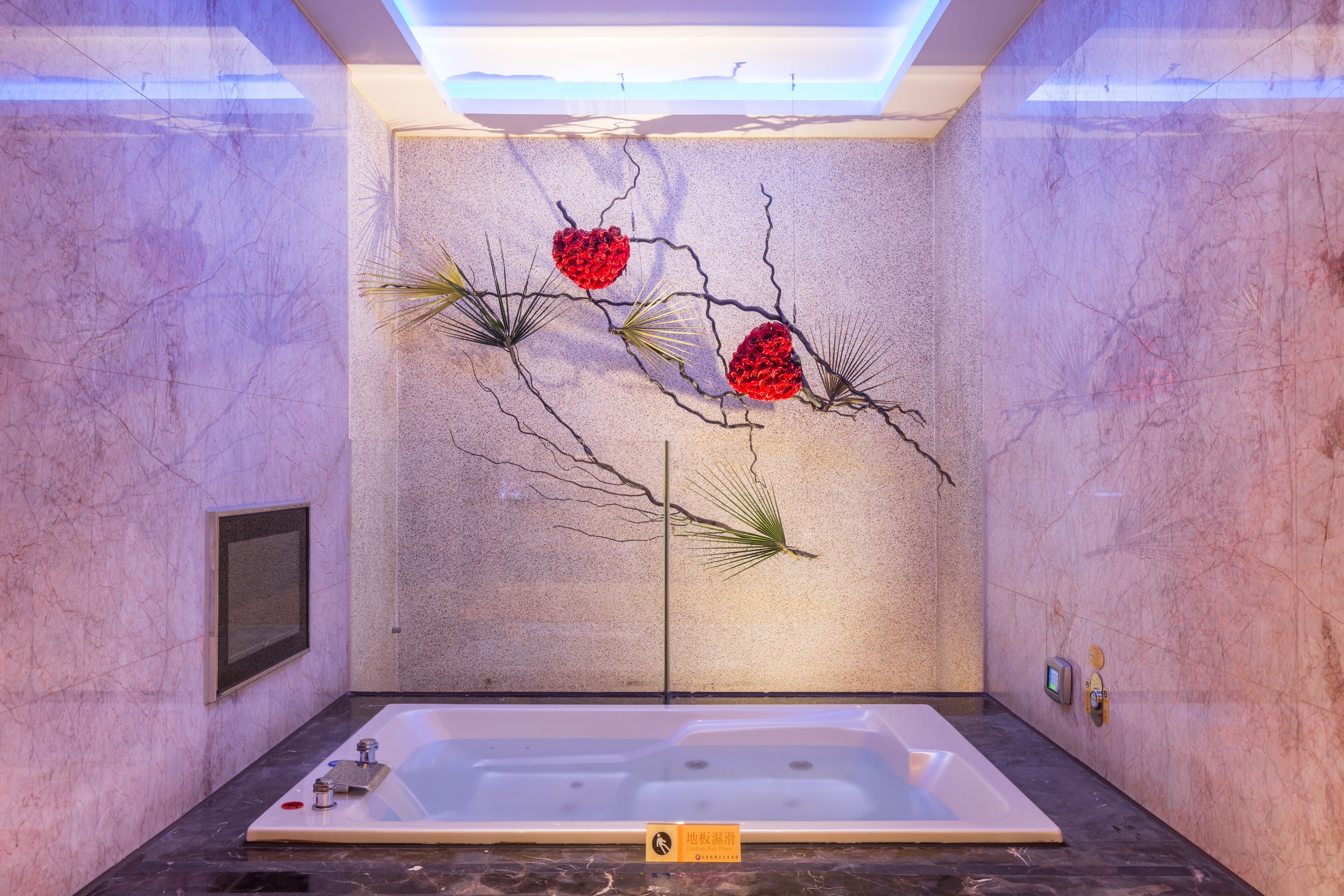 A modern bathroom with a large bathtub, decorative wall art, and a marble floor.