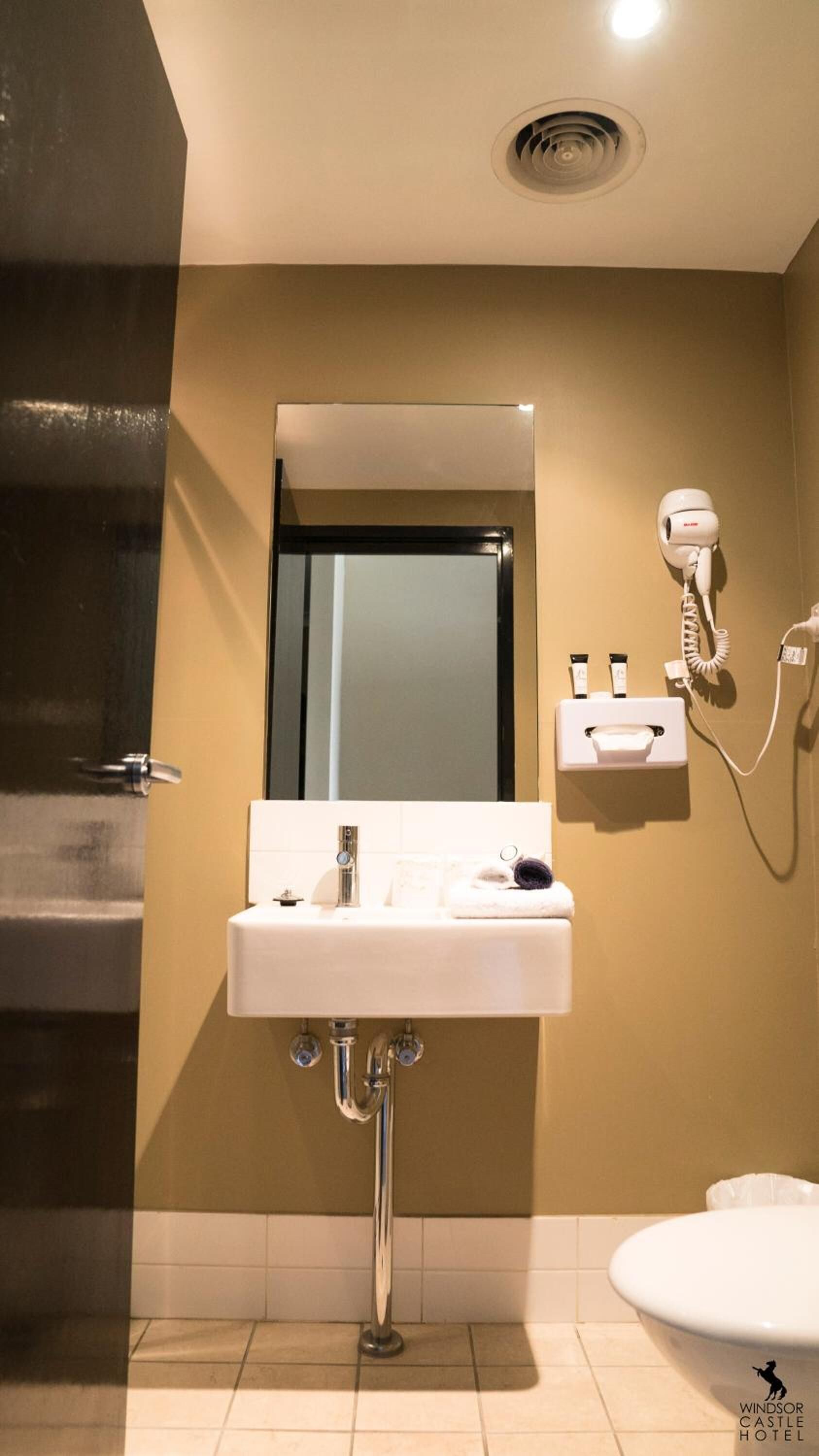 Une salle de bain avec un lavabo blanc, un miroir, un sèche-cheveux et des articles de toilette.