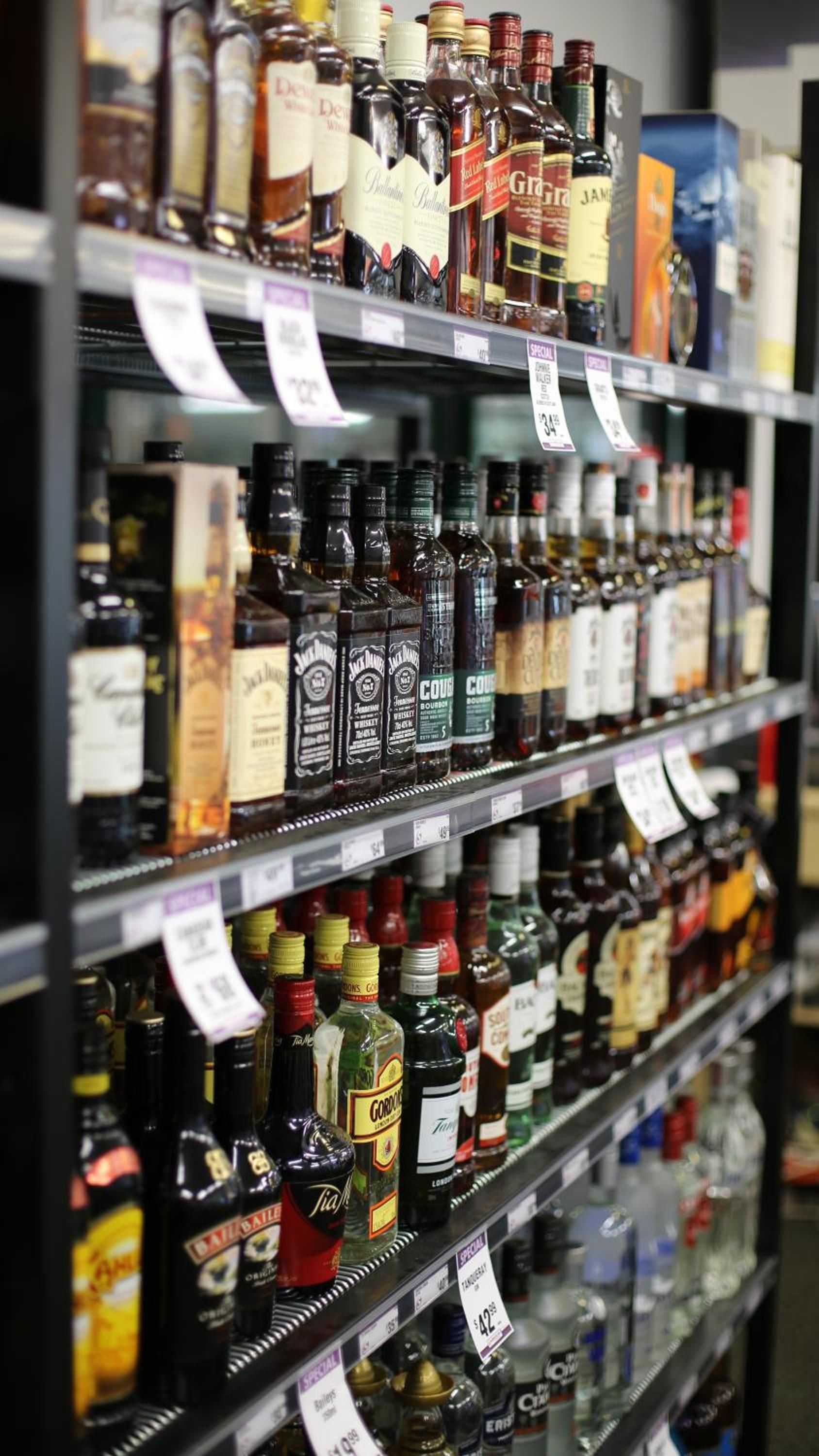 Estantes llenos de diferentes botellas de licor, cada una con su precio.