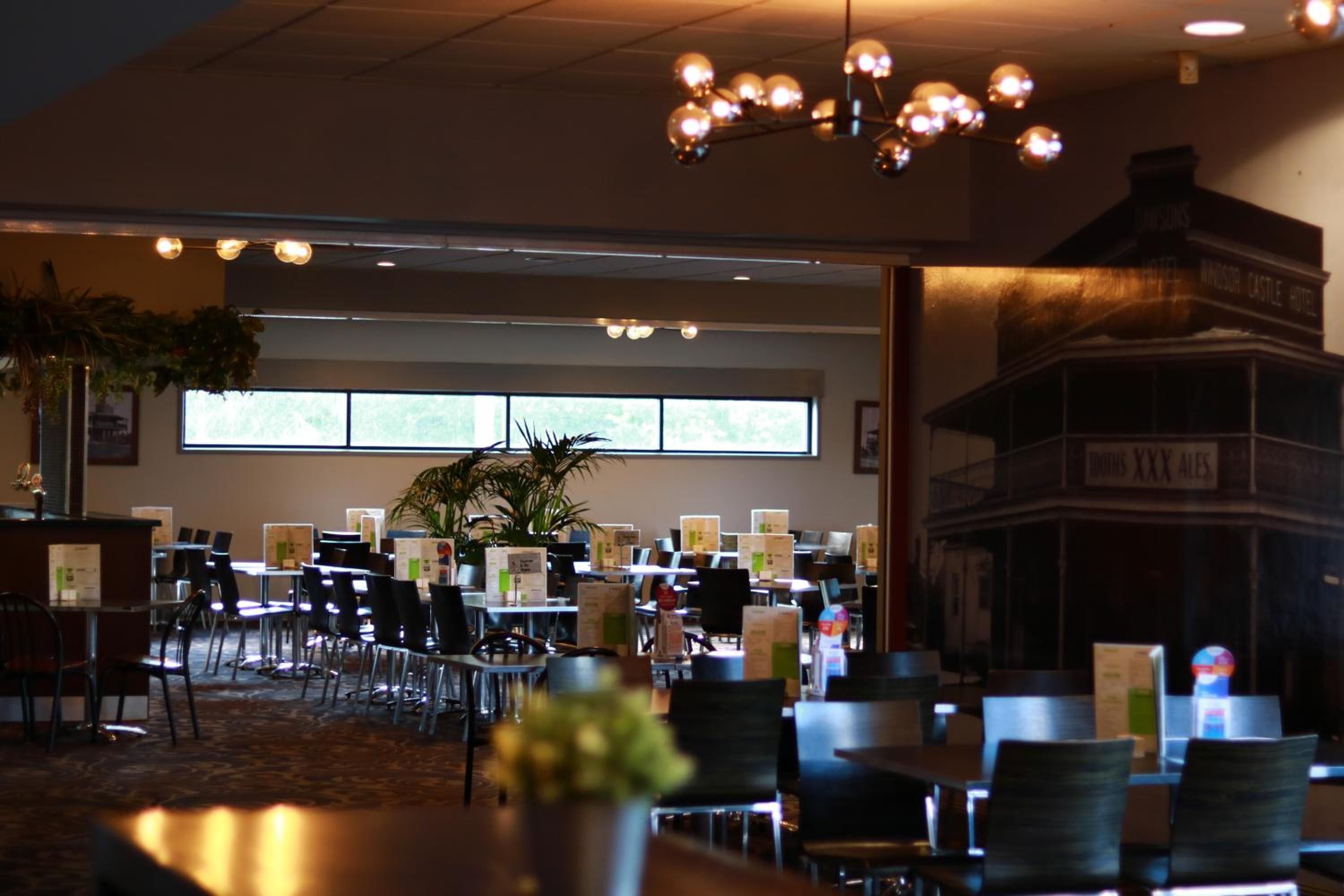 A hotel dining area with tables, chairs, and a large window.