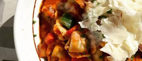 A bowl of pasta with a tomato-based sauce, garnished with herbs and topped with a dollop of cream.