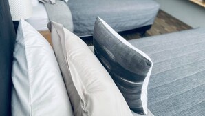 Una sala de estar moderna con un sofá gris y cojines blancos.