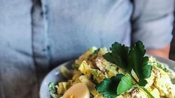 A person holding a bowl of salad with a boiled egg and greens.
