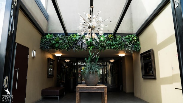 Un vestíbulo de hotel con una araña, plantas en macetas, un banco y cuadros en las paredes.