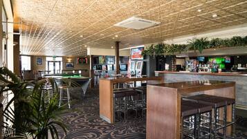 Un espace bar équipé de tables de billard, de tabourets et d’un comptoir avec un menu.