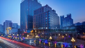 Un hôtel de grande hauteur, avec de nombreux étages, une cour intérieure et un parking.