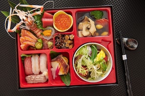 A bento box with various food items including fish, vegetables, and a salad. - Beijing Baifuyi Hotel Dongzhimen (Beijing)