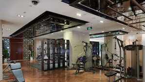Une salle de sport moderne équipée de matériel d’exercice, dotée d’un plancher en bois et d’un mur en verre.