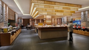 Un restaurant moderne doté d’un îlot central, de lambris en bois et d’une variété de plats présentés sur des étagères.