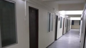 A long, narrow hallway with doors on both sides, tiled flooring, and overhead lighting.