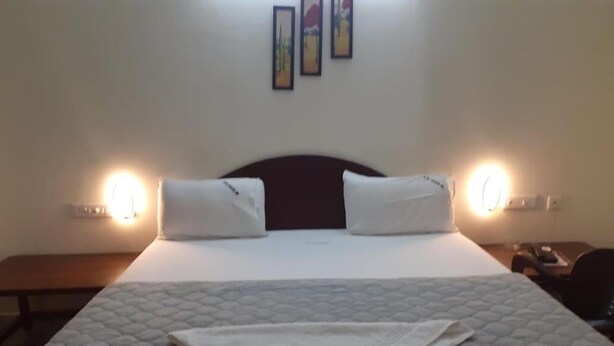 A neatly made bed with a quilted mattress, two pillows, and a folded blanket on a headboard.