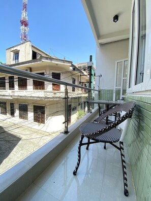 A balcony with a chair, a view of buildings, and a communication tower. - Hue Lovely Homestay  (Hue)