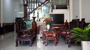 Amplia sala de estar con una imponente escalera, muebles de madera elegante y un televisor de pantalla plana grande.
