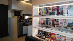 Cuina moderna amb microones, armaris i un rentapeus. Sota la cuina, hi ha prestatges que mostren revistes i llibres.