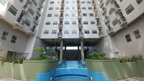 Edifici modern amb una piscina central, múltiples balcons i una paret exterior de verd vegetació.